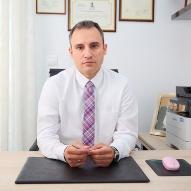 Ο νευρολόγος Βελίτσος Ιωάννης κάθεται σοβαρός στο γραφείο του, φορώντας άσπρο πουκάμισο και πολύχρωμη γραβάτα.
